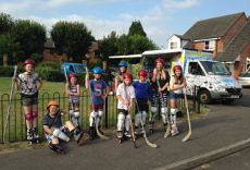 Children gather in a street holding hockey sticks, as part of the Sport for Streets initiative