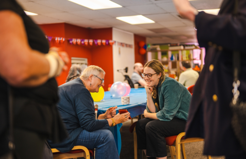 Picture of an older lady chatting in a community centre. New grants to help community groups with their energy bill costs funded by Oxfordshire County Council.