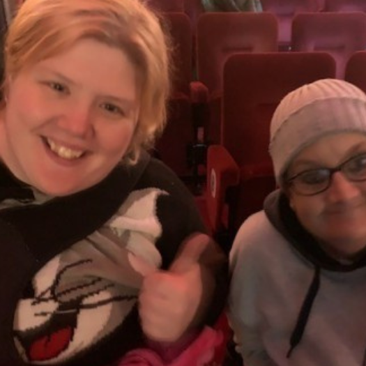 Two people, smiling and sitting together in a theatre.