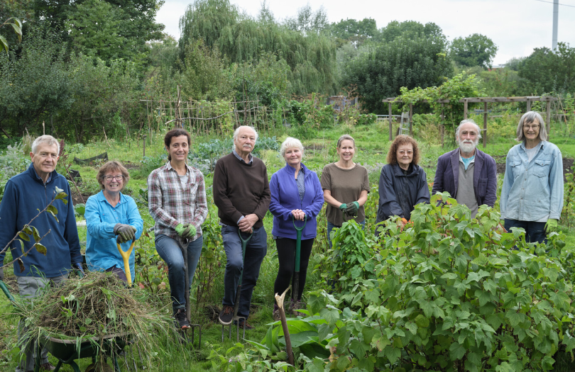 A group of people smiling while gardening together