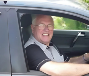 Man sitting in drivers seat in car and smiling.