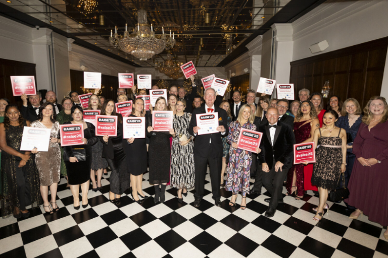 B4 Raise match news story 810×525 Group of guests in the Randolph ballroom holding up Raise'25 signs