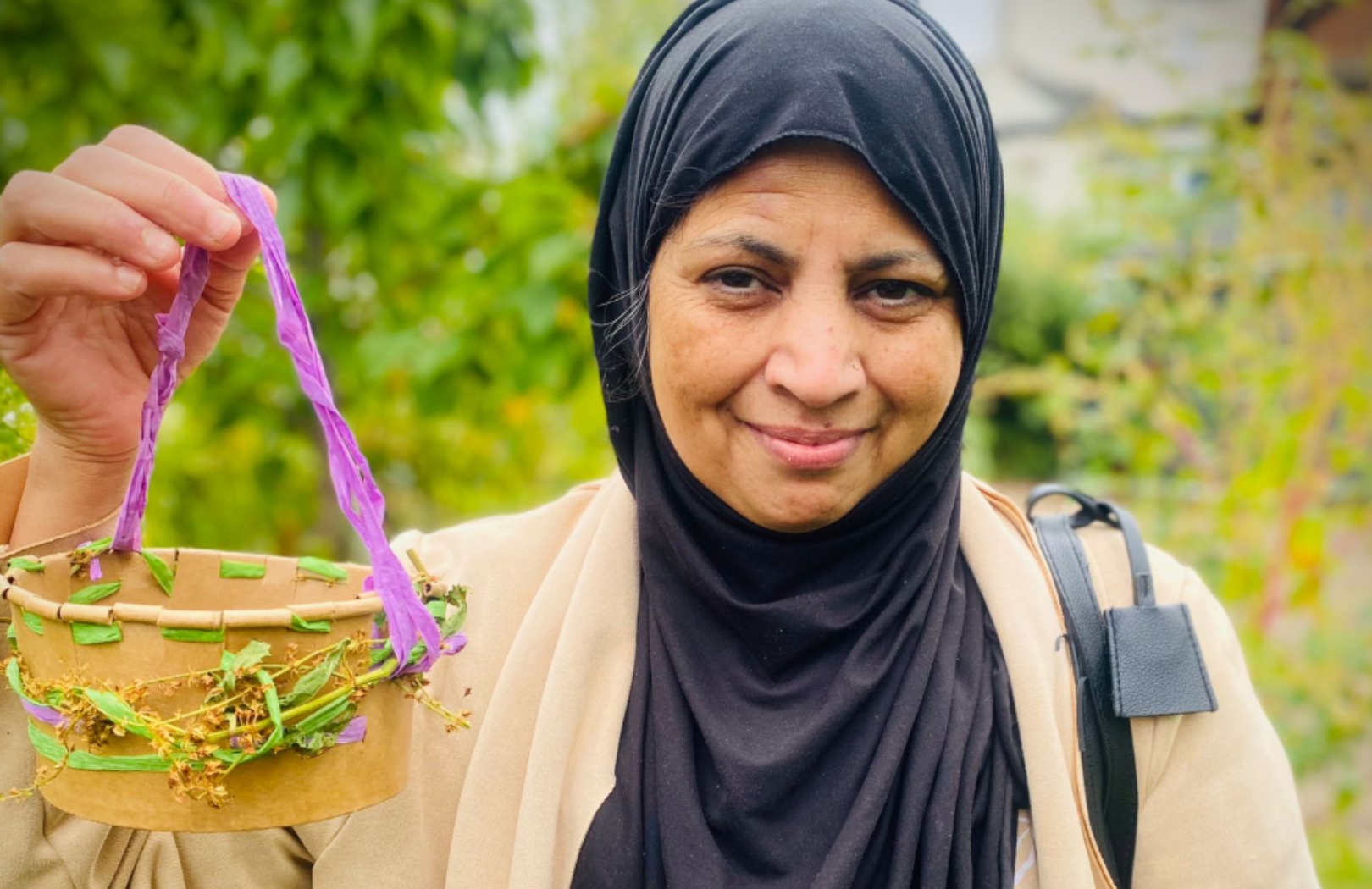 Thriving in Nature news story 810×525 Lady standing in garden holding a basket decorated with flowers.