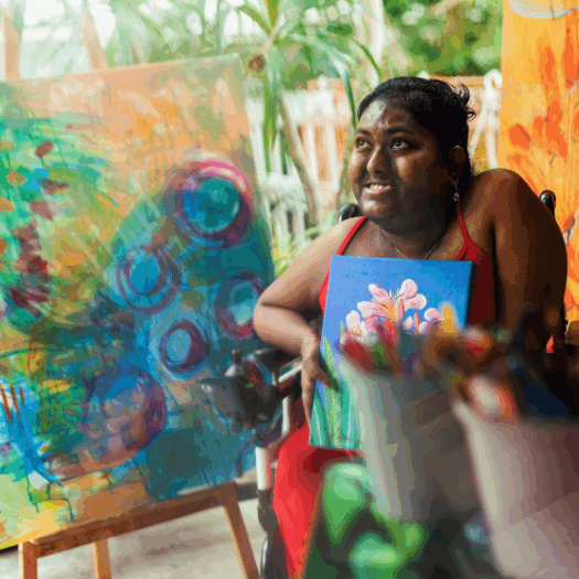 Young female person sitting in a wheelchair and painting a picture in an art studio.