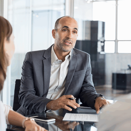 Three people sitting around a desk in an office.