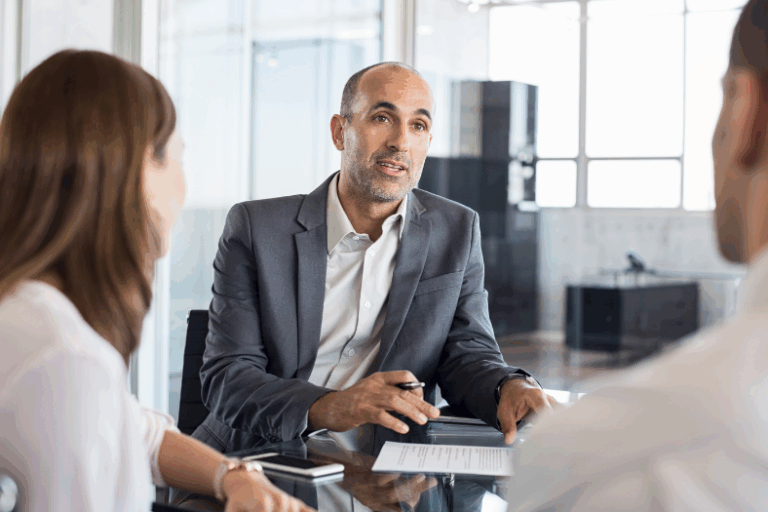 Three people sitting around a desk in an office.