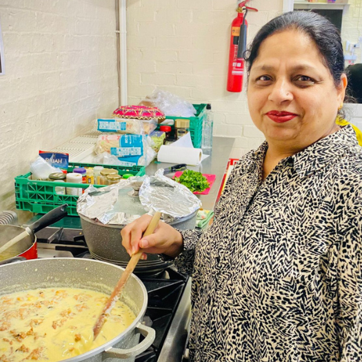 Sunrise Multicultural centre 1 Woman standing in front of a saucepan, stirring her cooking.