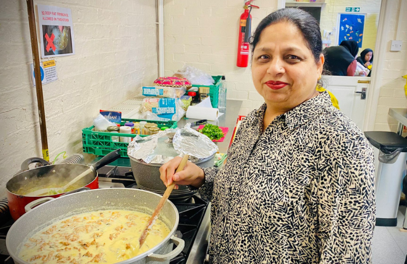 Woman standing in front of a saucepan, stirring her cooking.