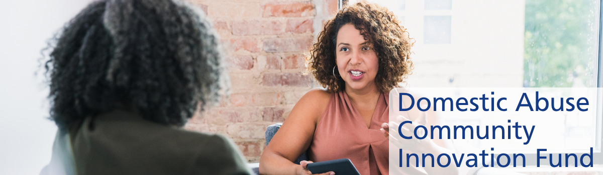 Domestic abuse grants header 1200x350 (1) Two women sitting down and talking together.