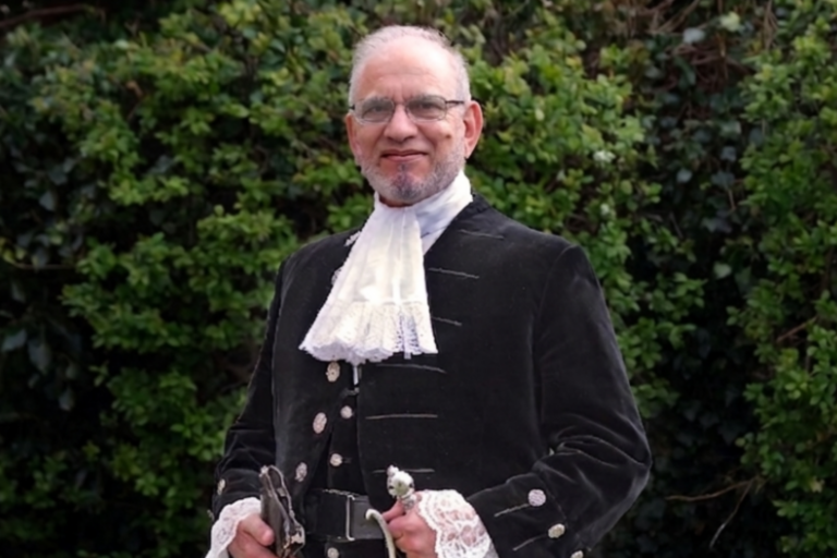 The High Sheriff, Jawaid Malik, dressed in the High Sheriff traditional uniform of black decorated jacket and lace shirt.