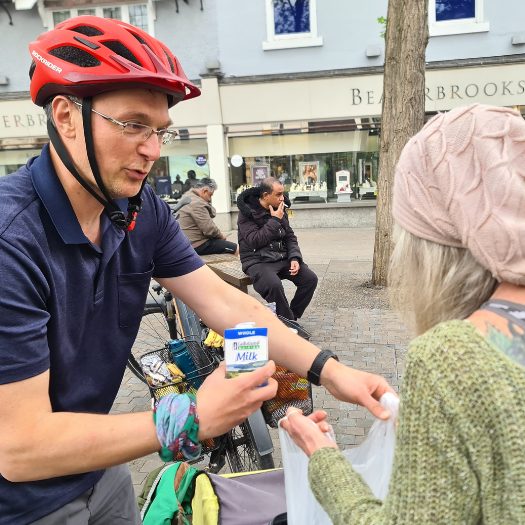 Randal Foundation news story 810×525 Man on bike filling up a bag of food for someone.