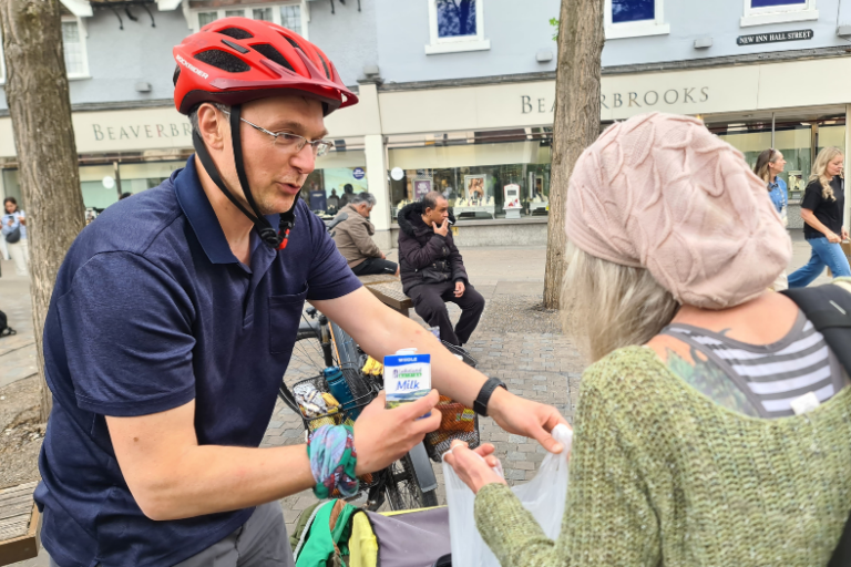 Man on bike filling up a bag of food for someone.