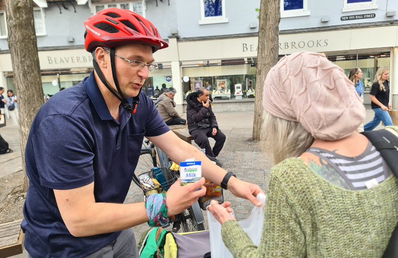 Man on bike filling up a bag of food for someone.