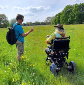 Person in electric wheelchair travelling across a grassy field.